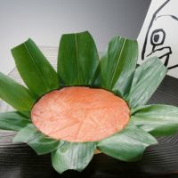 富山名産品ますのすしの笹が開かれ、鱒の身が美味しそうに見えています。