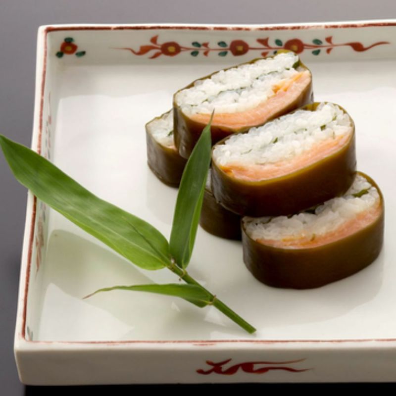 カットされたますのいぶしすしの断面が見え、昆布・鱒・大葉・お米が美味しそうお皿に並んでいます。