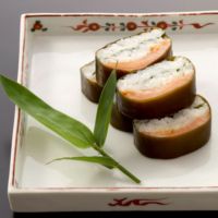 カットされたますのいぶしすしの断面が見え、昆布・鱒・大葉・お米が美味しそうお皿に並んでいます。