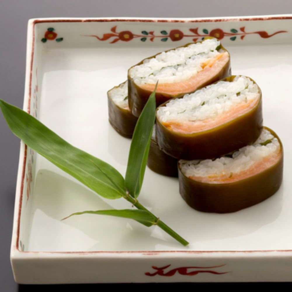 カットされたますのいぶしすしの断面が見え、昆布・鱒・大葉・お米が美味しそうお皿に並んでいます。